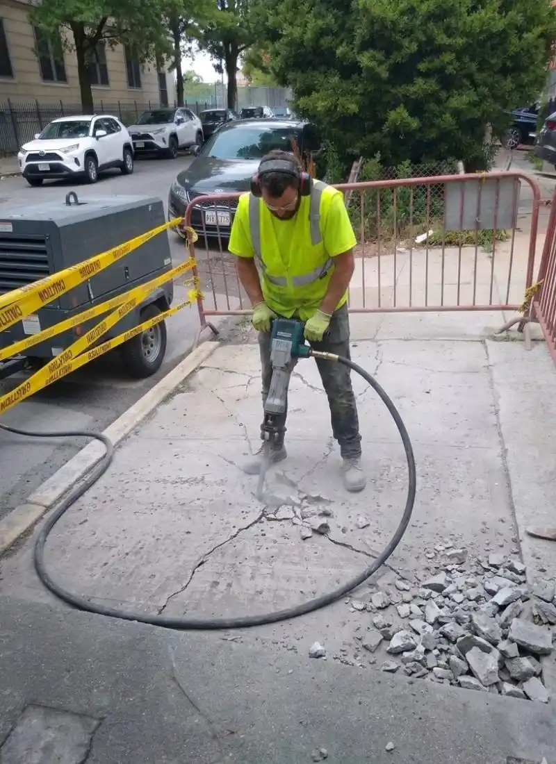 sidewalk contractor breaking damaged concrete slabs before replacement work