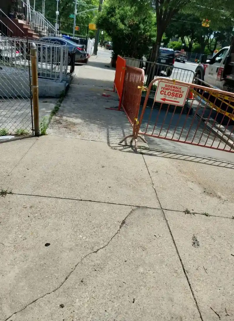 temporary sidewalk closure and safety barriers during concrete repair work in the Bronx